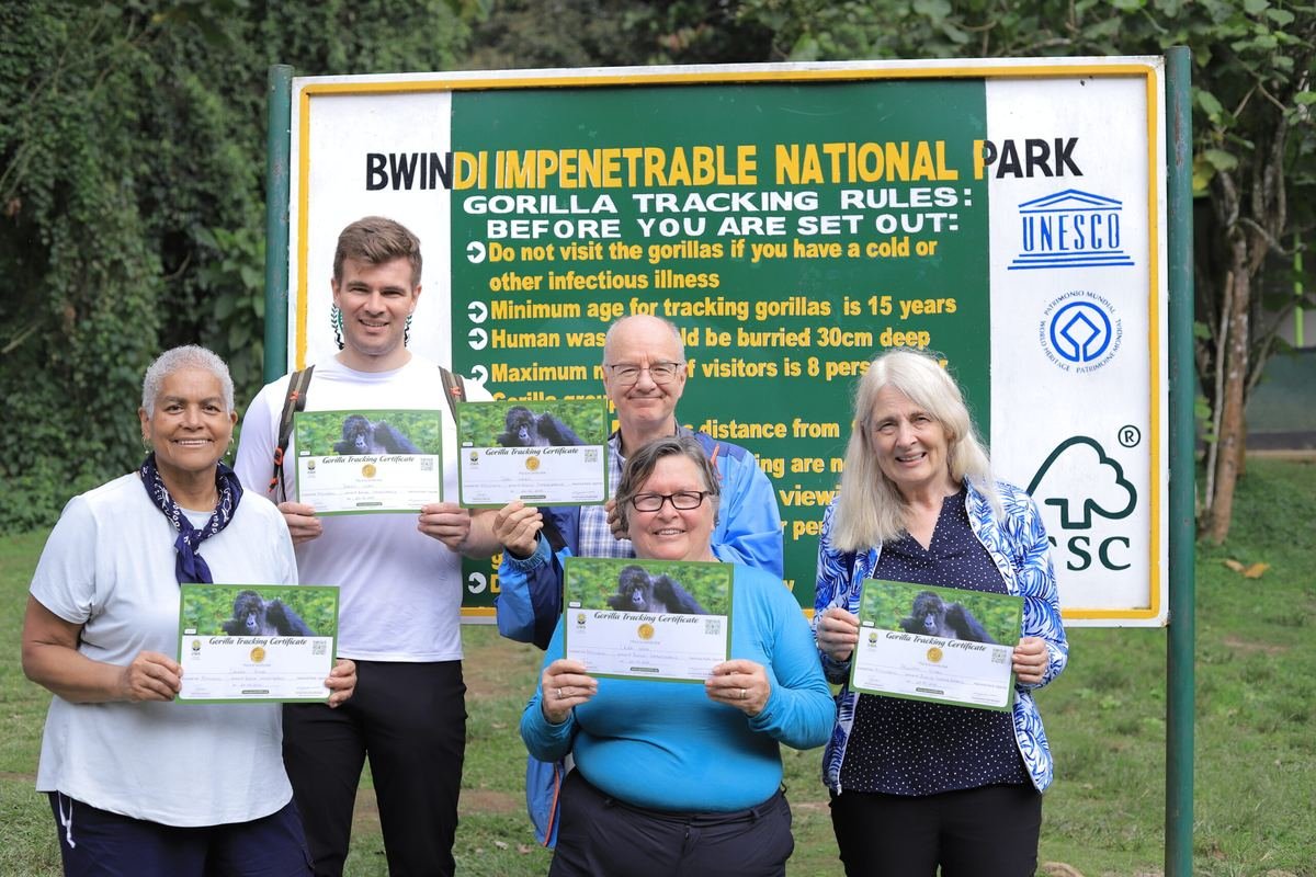 Bashem travellers holding their gorilla trekking certificates at the Bwindi Impenetrable National Park sign