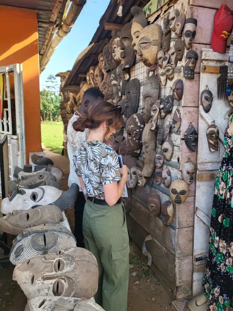 A traveller looking at carved wooden masks on a roadside craft stall